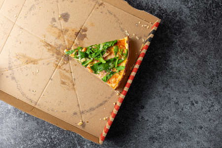 above view of last slice of pizza in cardboard box on stone kitchen counterの写真素材