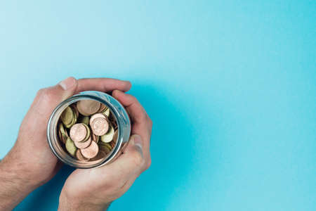above view of hands holding jar filled with small change, savings and investment concept