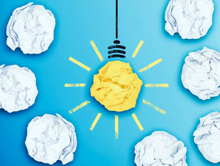 illuminated light bulb in midst of crumpled paper balls, having an idea conceptの写真素材