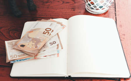 bundels of money on open notebook against old wooden deskの写真素材