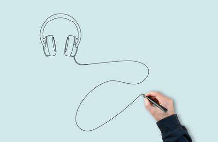 man using black marker to draw headphones with a single line or single strokeの写真素材