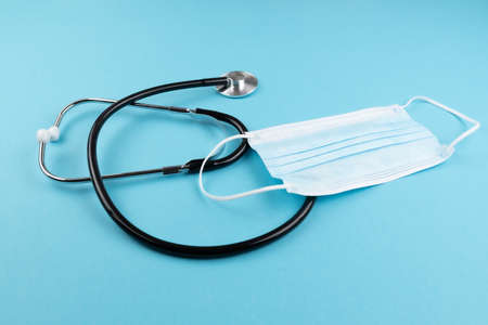 high angle view of stethoscope and surgical mask on blue background, covid-19 coronavirus and respiratory disease conceptの写真素材