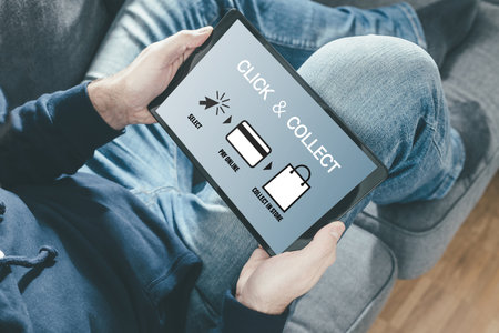 close-up of person on sofa holding tablet computer for online shopping using a click and collect serviceの写真素材