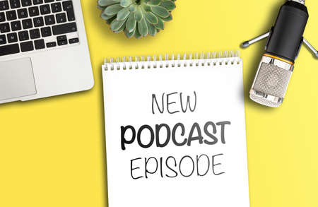 top view of text NEW PODCAST EPISODE on notepad on desk with microphone and laptop computer, podcasting conceptの写真素材