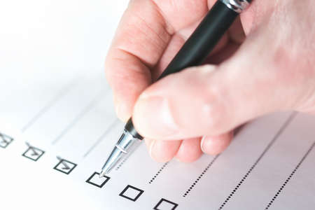 close-up of person ticking off checklist with ballpoint penの写真素材