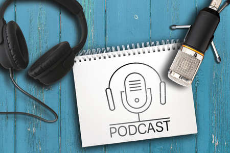 top view of headphones, microphone and note pad with PODCAST logo on rustic wooden tableの写真素材