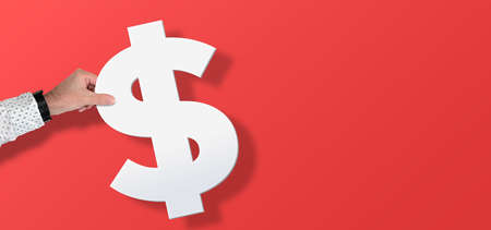 hand holding large Dollar symbol against red background with copy space, financial conceptの写真素材