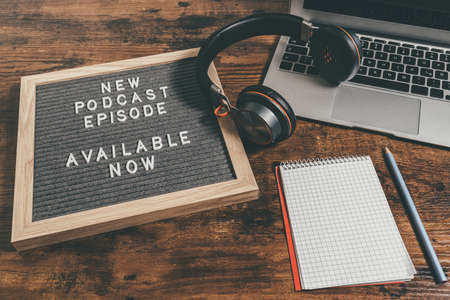 letter board with text NEW PODCAST EPISODE on wooden table with laptop, note pad and headphones, podcasting conceptの写真素材
