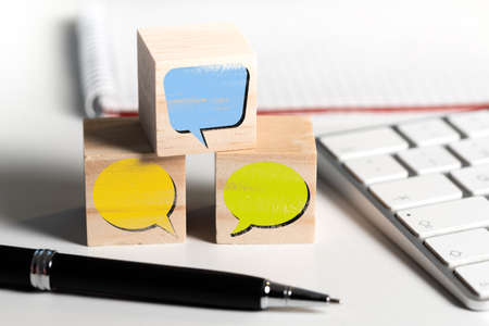 empty speech bubbles on wooden blocks on office desk, communication concept