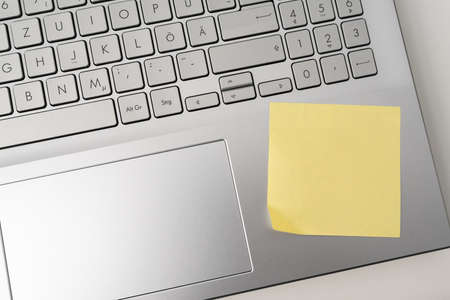 directly above view of blank yellow sticky note on laptop computer