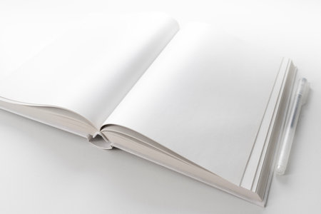 high angle view of open book with blank white pages on white desk with pen
