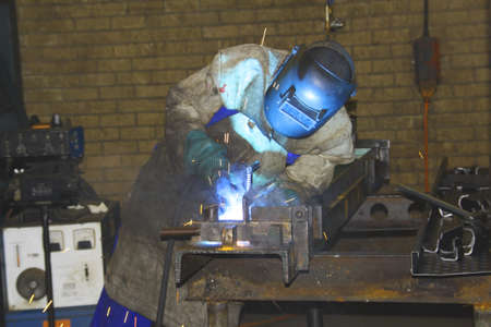 Man changing position for a better angle while arc-welding