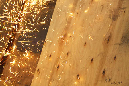 Sparks from a grinder landing on a wooden panel