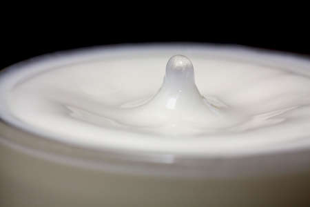 Droplet of water in a glass of milkの写真素材