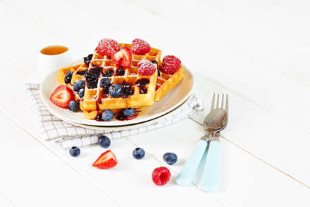 Belgian waffles with berries and hone on wooden tableの写真素材