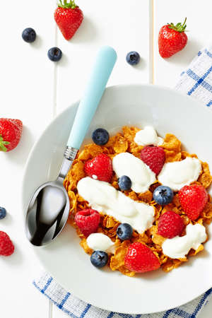 Cereals with yogurt and berries on white wooden table, top view