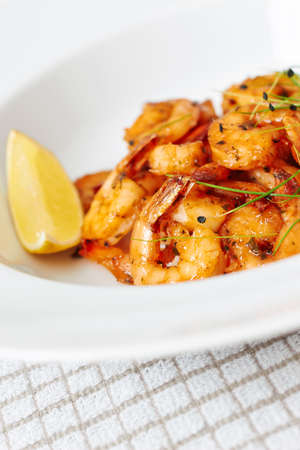 Shrimps dish on white plate with slice of lemonの写真素材
