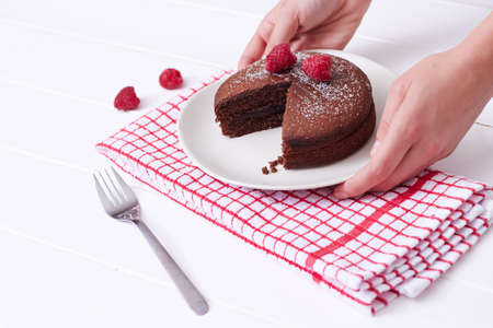 Hands serving chocolate sponge cake on wooden tableの写真素材