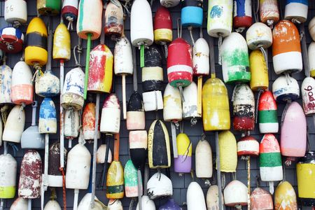 A group of lobster buoys hanging on the side of a building in the harbor of Provincetown, Massachusettsの写真素材