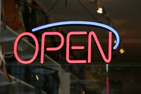 A red and blue open sign in the window of a store