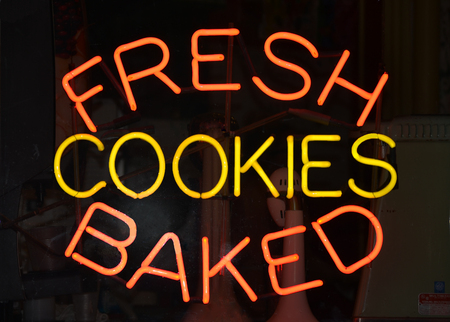 An orange and yellow neon sign reading Fresh Baked Cookies