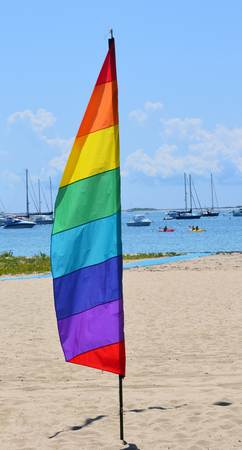 A gay pride feather flag against the background of a marina in Provincetown, Massachusettsの写真素材