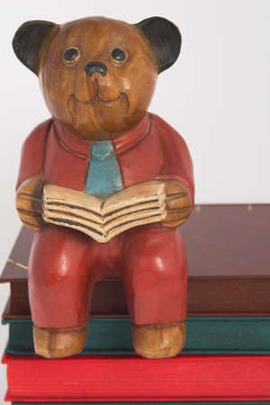 carved wooden bear reading a book sitting on pile of booksの写真素材