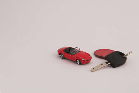 Red toy car with car key and red fob on white backgroundの写真素材