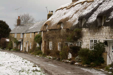 A terrace of old stone cottages with slate & thatch roofs in the snow.の写真素材