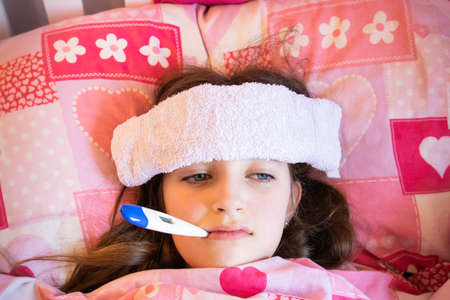 sick girl in bed with thermometer