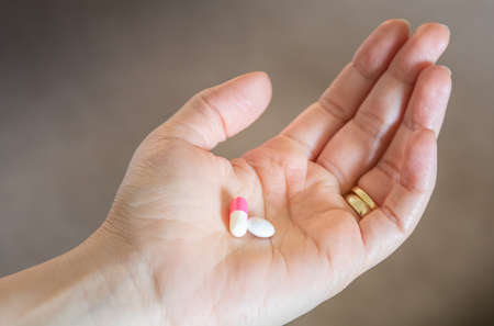 Hand holding different pills for medication of illnessの写真素材