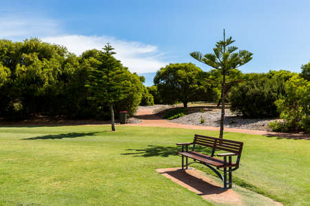 Empty park bench in local suburban park on beautiful spring day in Dalyellup Western Australiaの写真素材