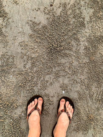 Feet in thongs looking down on Sand Bubbler Crab pellets on Cable Beach Broomeの写真素材