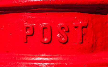 A close-up of the word â€˜Postâ€™ on a red Post Box in the England.