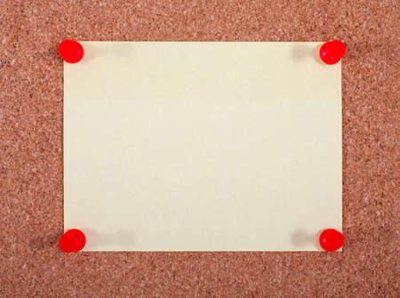 A yellow note page pinned to a noticeboard.の写真素材