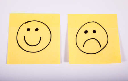 Happy and Sad Faces on Two Pieces of Memo Paper.の写真素材