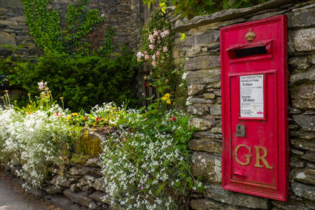 An old-fashioned post box in a traditional English countryside village.