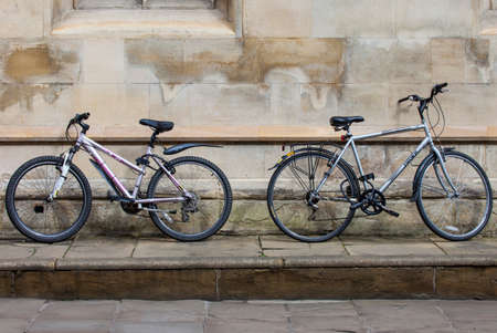 CAMBRIDGE, UK - APRIL 8TH 2016: Two bicycles propped up against a wall in the university city of Cambridge in the UK, on 8th April 2016.  Bicycles are the quickest and cheapest mode of transport in and around the town.のeditorial素材