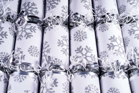 A studio shot of a set of Christmas Crackers or otherwise known as Bon Bons.  A cracker consists of a cardboard tube wrapped in a decorated twist of paper with a gift in the central chamber.の写真素材