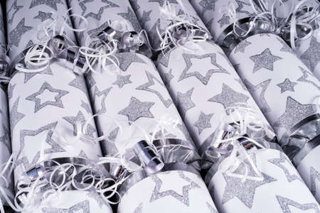 A studio shot of a set of Christmas Crackers or otherwise known as Bon Bons.  A cracker consists of a cardboard tube wrapped in a decorated twist of paper with a gift in the central chamber.の写真素材