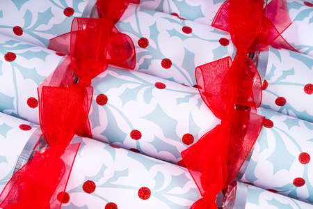 A studio shot of Christmas Crackers or otherwise known as Bon Bons.  A traditional cracker consists of a cardboard tube wrapped in a brightly decorated twist of paper with a gift in the central chamber.の写真素材