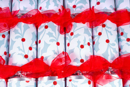 A studio shot of Christmas Crackers or otherwise known as Bon Bons.  A traditional cracker consists of a cardboard tube wrapped in a brightly decorated twist of paper with a gift in the central chamber.の写真素材