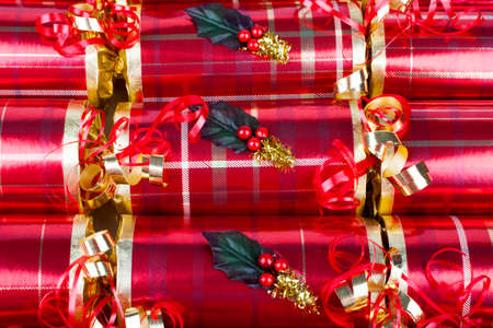 A studio shot of Christmas Crackers or otherwise known as Bon Bons.  A traditional cracker consists of a cardboard tube wrapped in a brightly decorated twist of paper with a gift in the central chamber.の写真素材