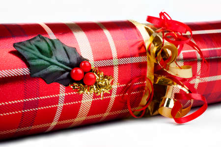 A studio shot of a Christmas Cracker or otherwise known as a Bon Bon.  A traditional cracker consists of a cardboard tube wrapped in a brightly decorated twist of paper with a gift in the central chamber.の写真素材