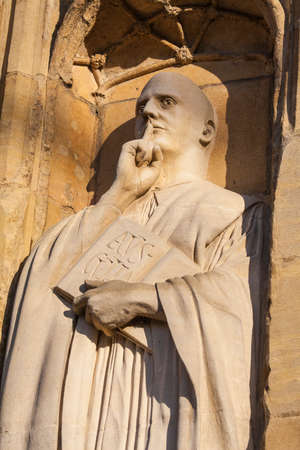 A sculpture of St. Benedict on the exterior of the West Porch of Norwich Cathedral in the historic city of Norwich, UK.のeditorial素材
