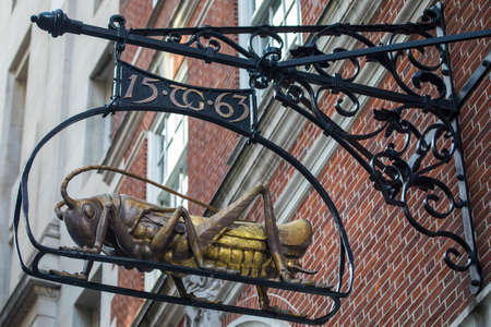 A Grasshopper sculpture hanging on Lombard Street in London, UK.  The Grasshopper is the representation of the family crest of the once occupier Sir Thomas Gresham.のeditorial素材