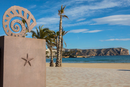 XABIA, SPAIN - APRIL 12TH 2018: A bronze sea shell sculpture located on the promenade along the Arenal in Xabia, also known as Javea, in Spain, on 12th April 2018.  Cap de Sant Antoni can be seen in the disatnce.のeditorial素材
