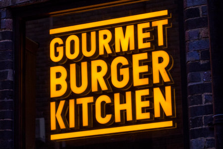 London, UK - April 1st 2019: The company logo of Gourmet Burger Kitchen above the entrance to one of their restaurants in London, UK.のeditorial素材