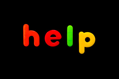 The word HELP spelt with brightly coloured letters over a black background. の写真素材