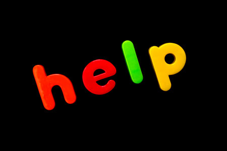 The word HELP spelt with brightly coloured letters over a black background. の写真素材